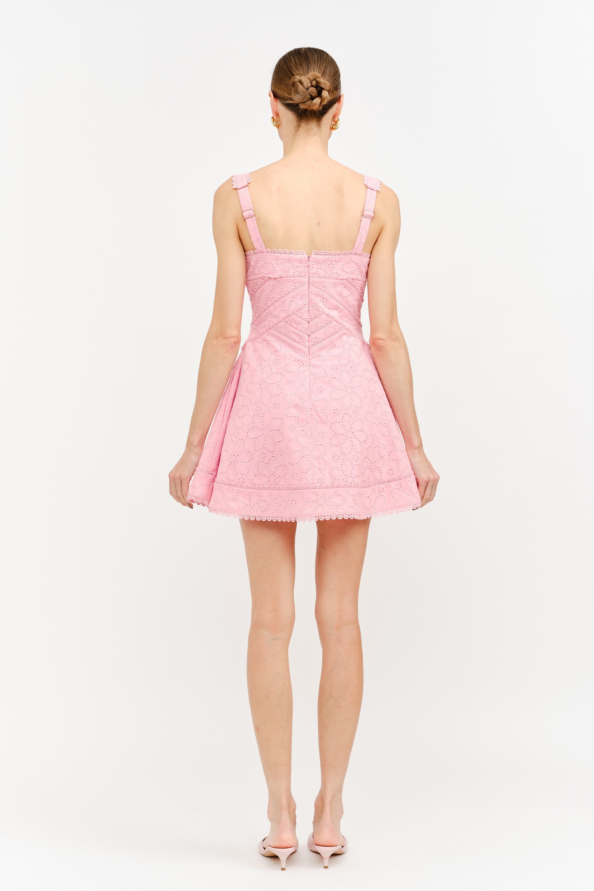 Back view of a person wearing a pink dress on a white background