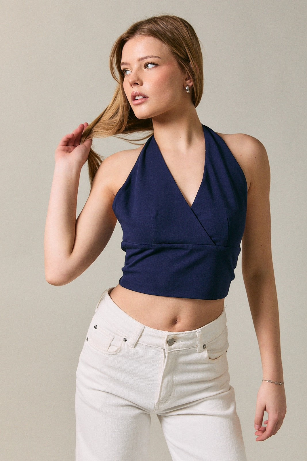 Woman wearing a navy halter top and white pants against a neutral background