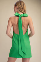 Green dress with a large bow on a beige background