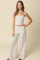 Woman wearing a polka dot top and pants on a beige background