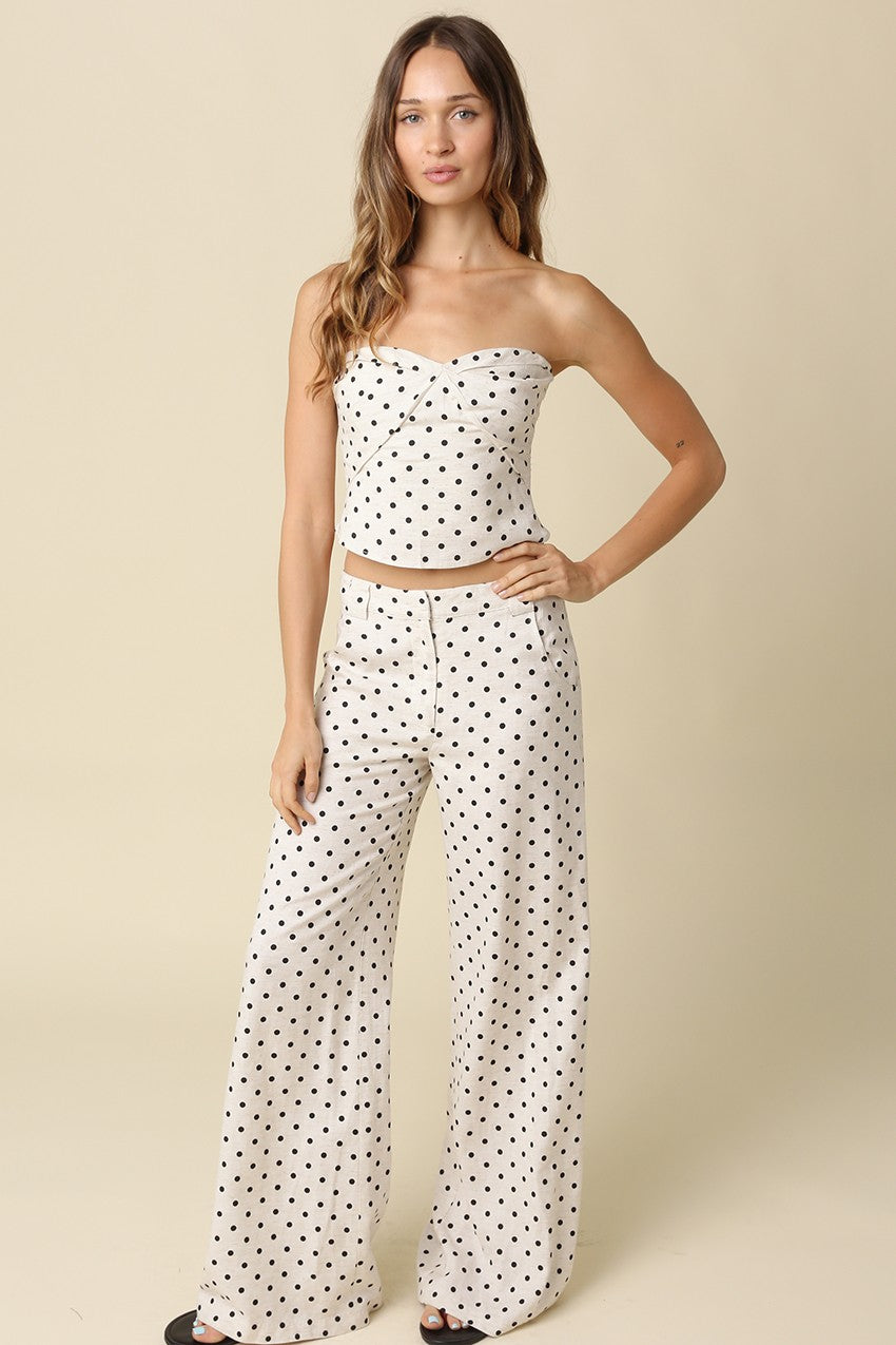 Woman wearing a polka dot top and pants on a beige background