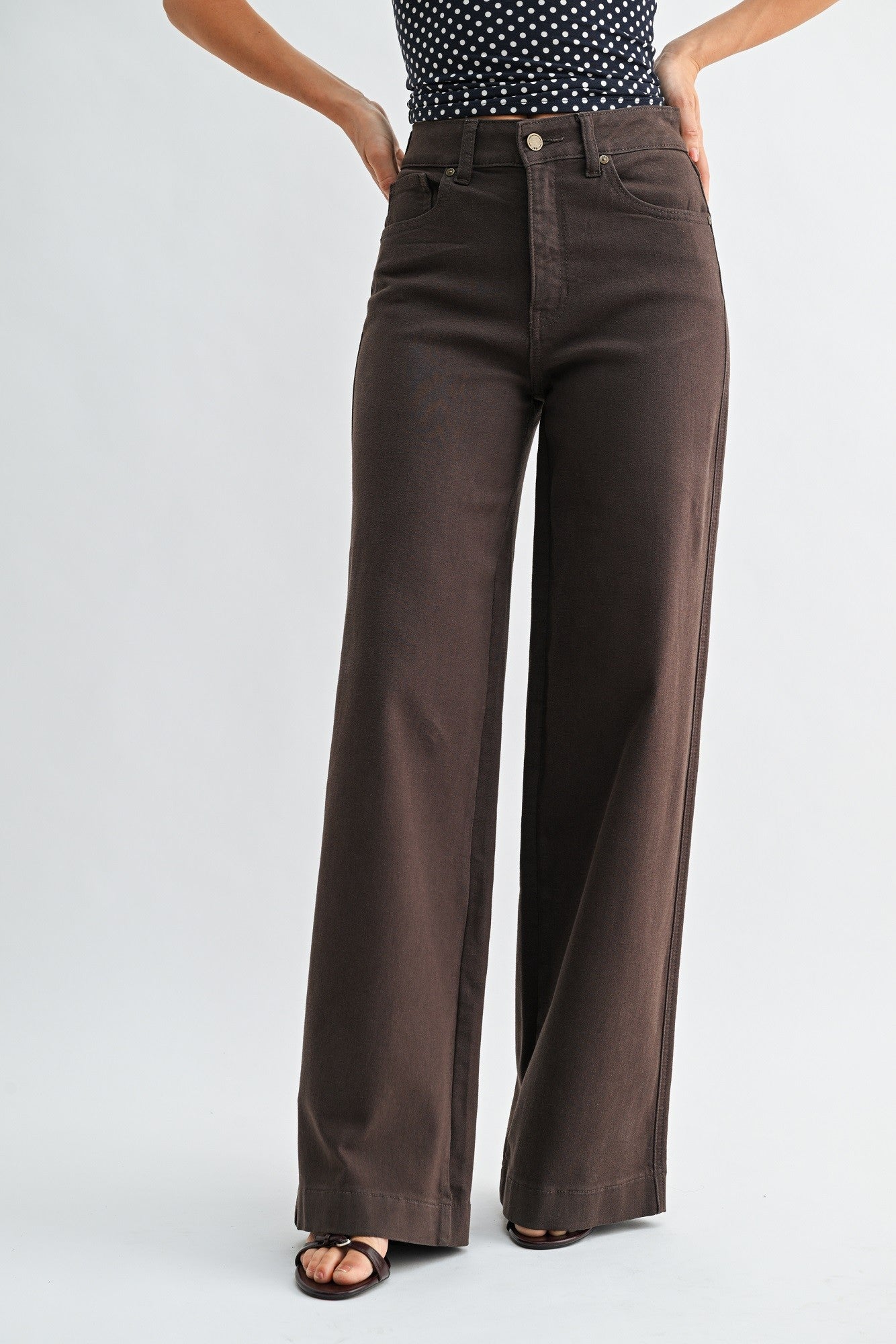 Brown wide-leg jeans worn by a person on a white background