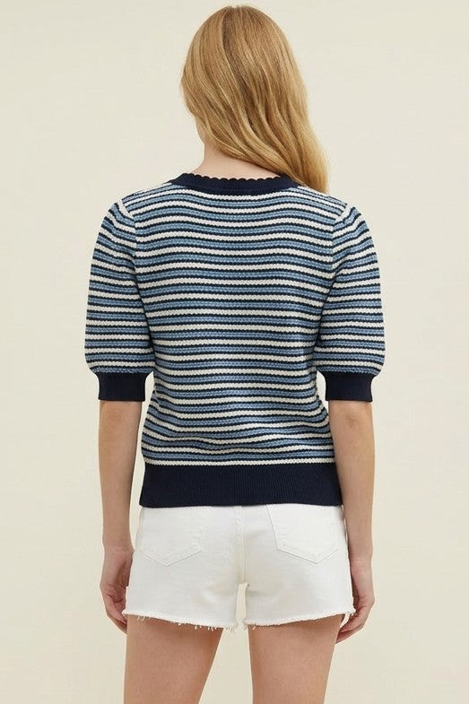 Woman wearing a striped sweater and white shorts on a plain background
