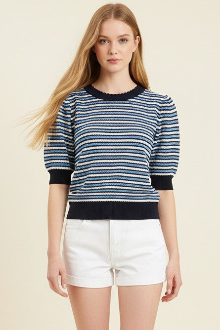 Woman wearing a blue and white striped sweater with black trim on a beige background