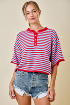 Woman wearing a red and white striped shirt with denim shorts on a beige background