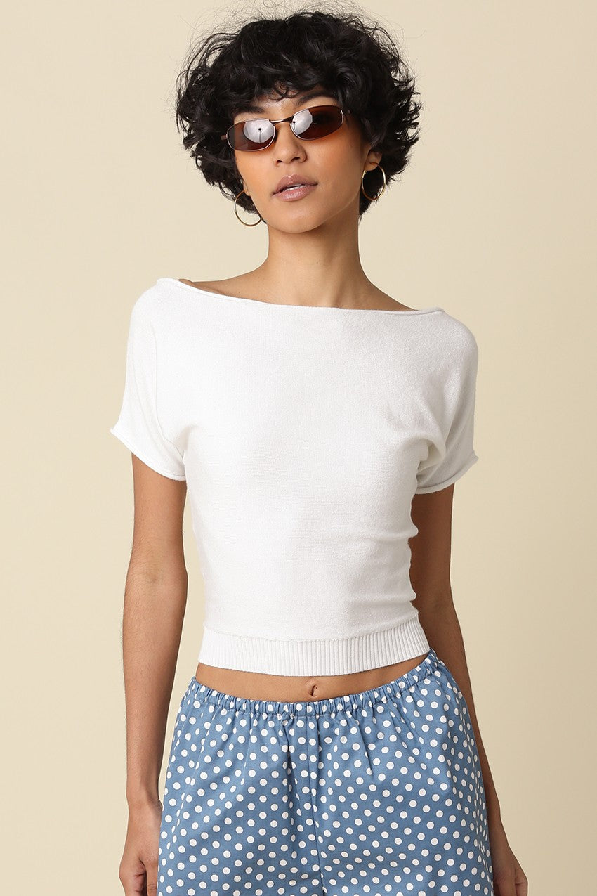 Woman wearing a white top and blue polka dot pants against a beige background