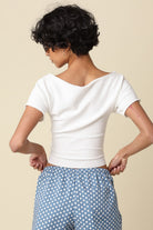 Person wearing a white top and blue polka dot pants on a beige background
