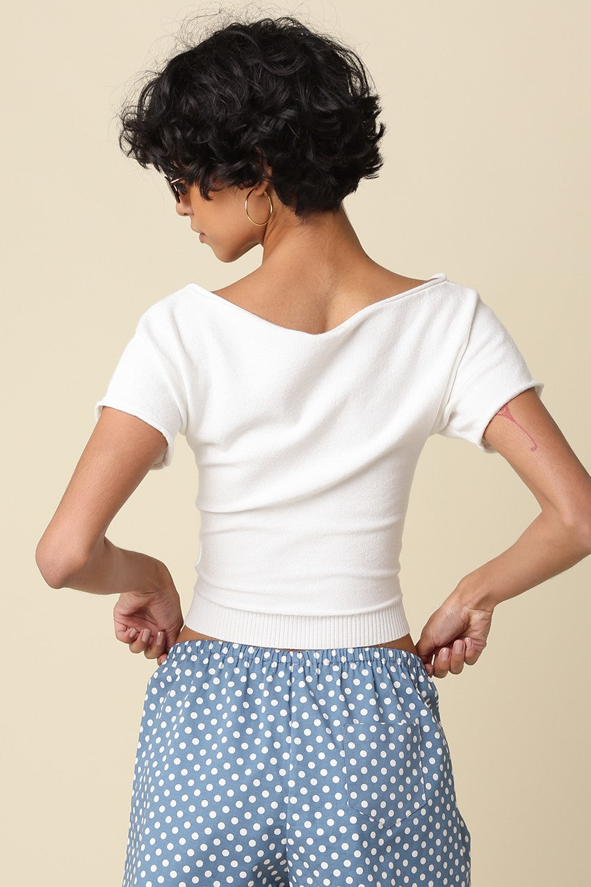 Person wearing a white top and blue polka dot pants on a beige background