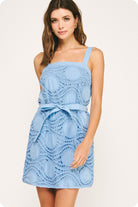 Woman wearing a light blue lace dress on a white background