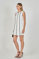 Woman wearing a white dress with black trim on a gray background