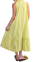 Woman wearing a yellow and white striped dress against a beige background