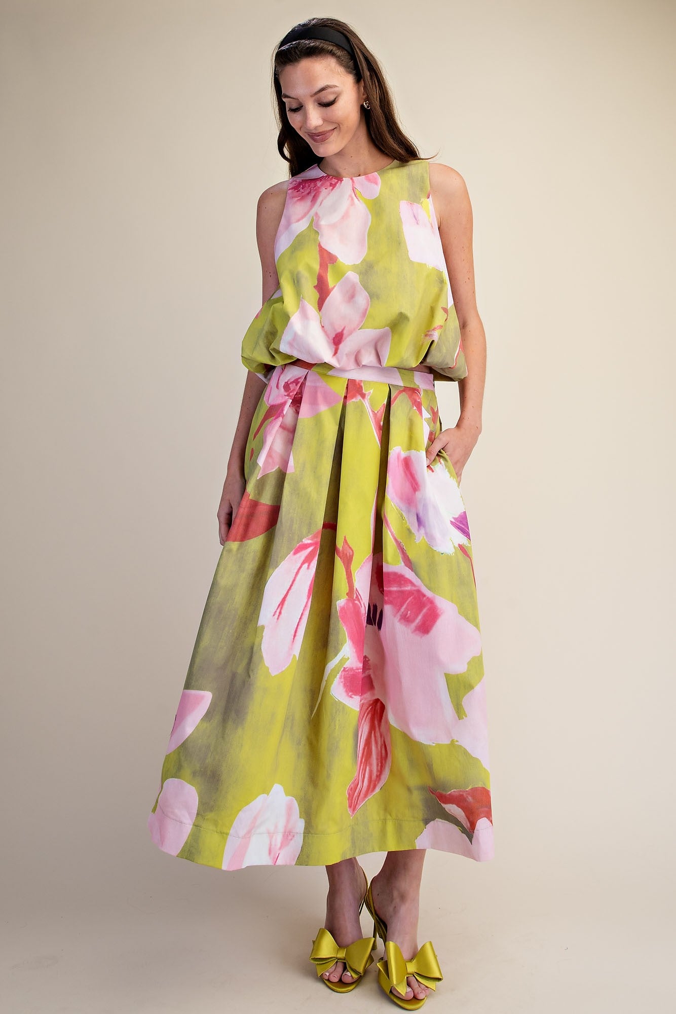 Woman wearing a floral dress with pink and green colors on a beige background