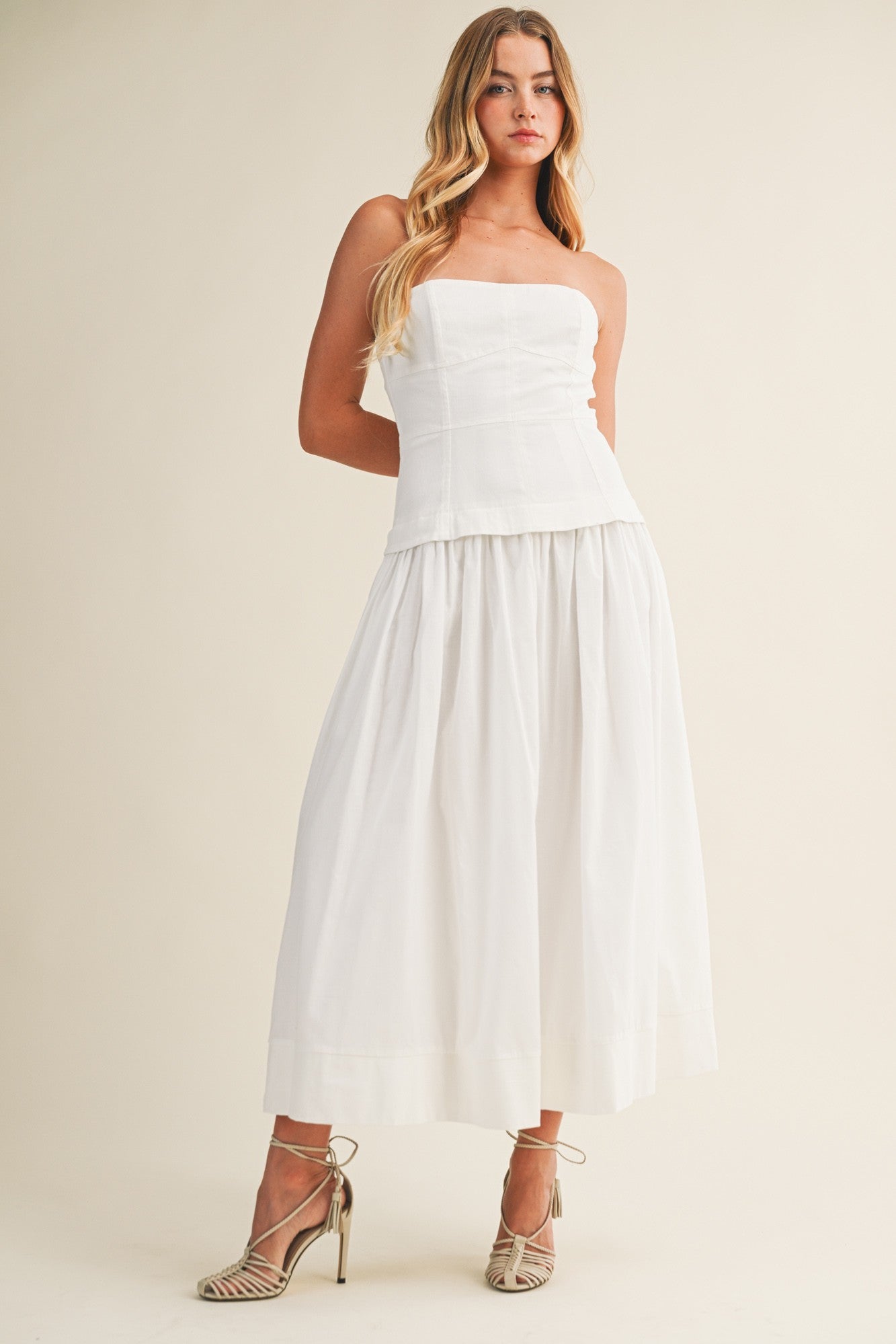 Woman wearing a strapless white dress against a plain background