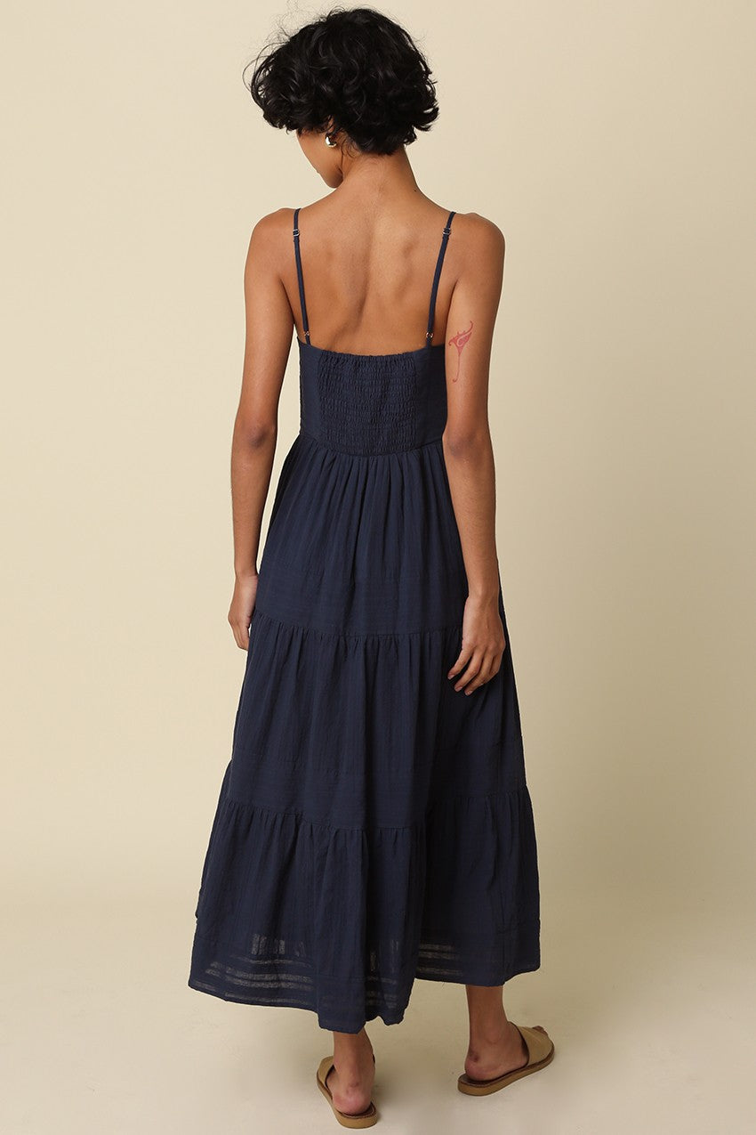 Woman wearing a navy blue dress with thin straps on a beige background