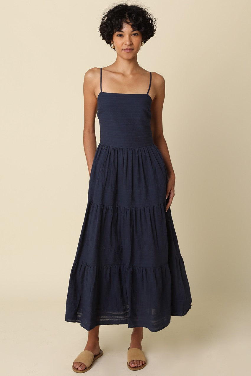 Woman wearing a navy blue dress against a beige background
