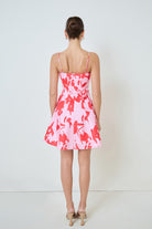 Woman wearing a pink and white patterned dress against a white background