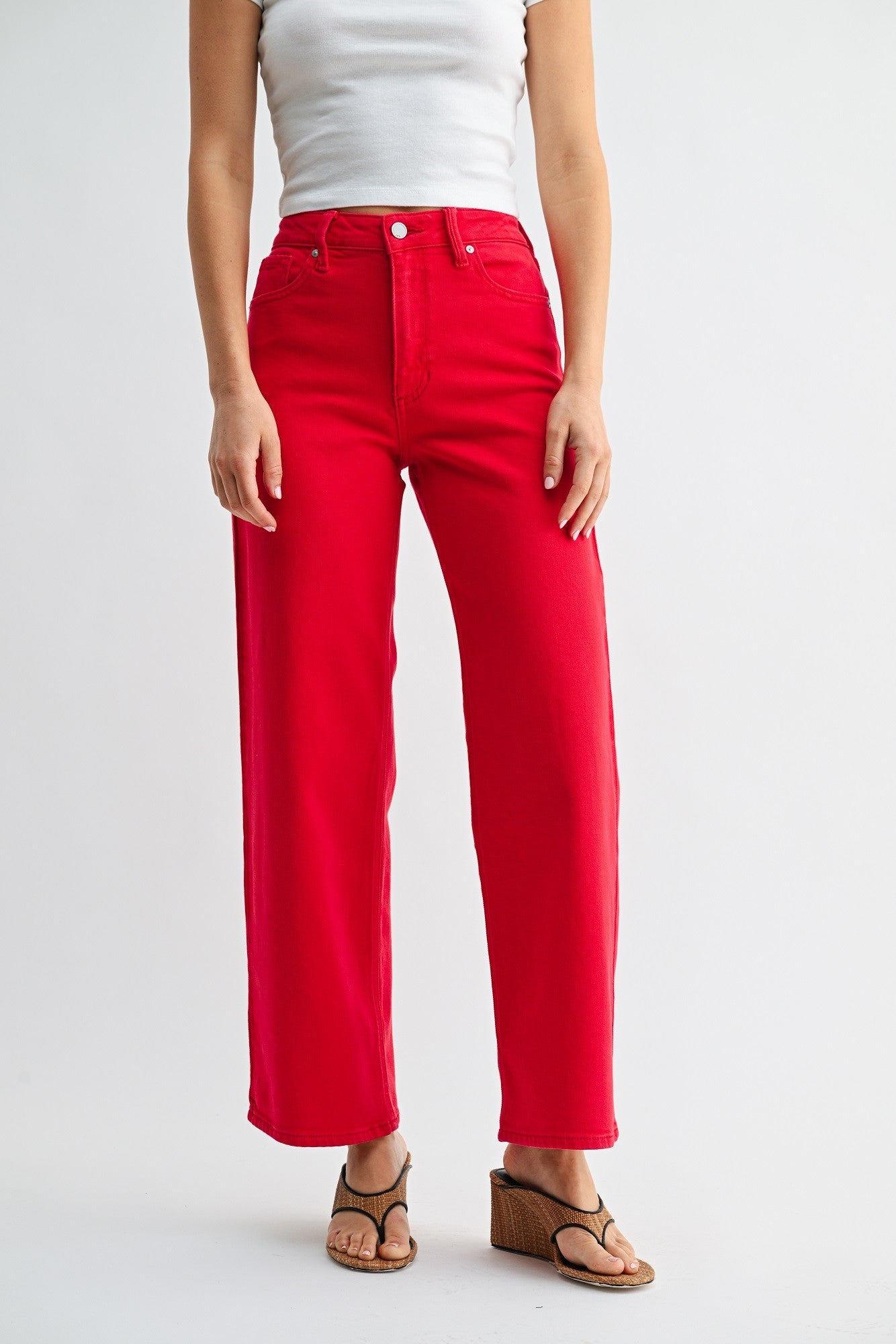 Person wearing bright red pants and a white top on a light gray background