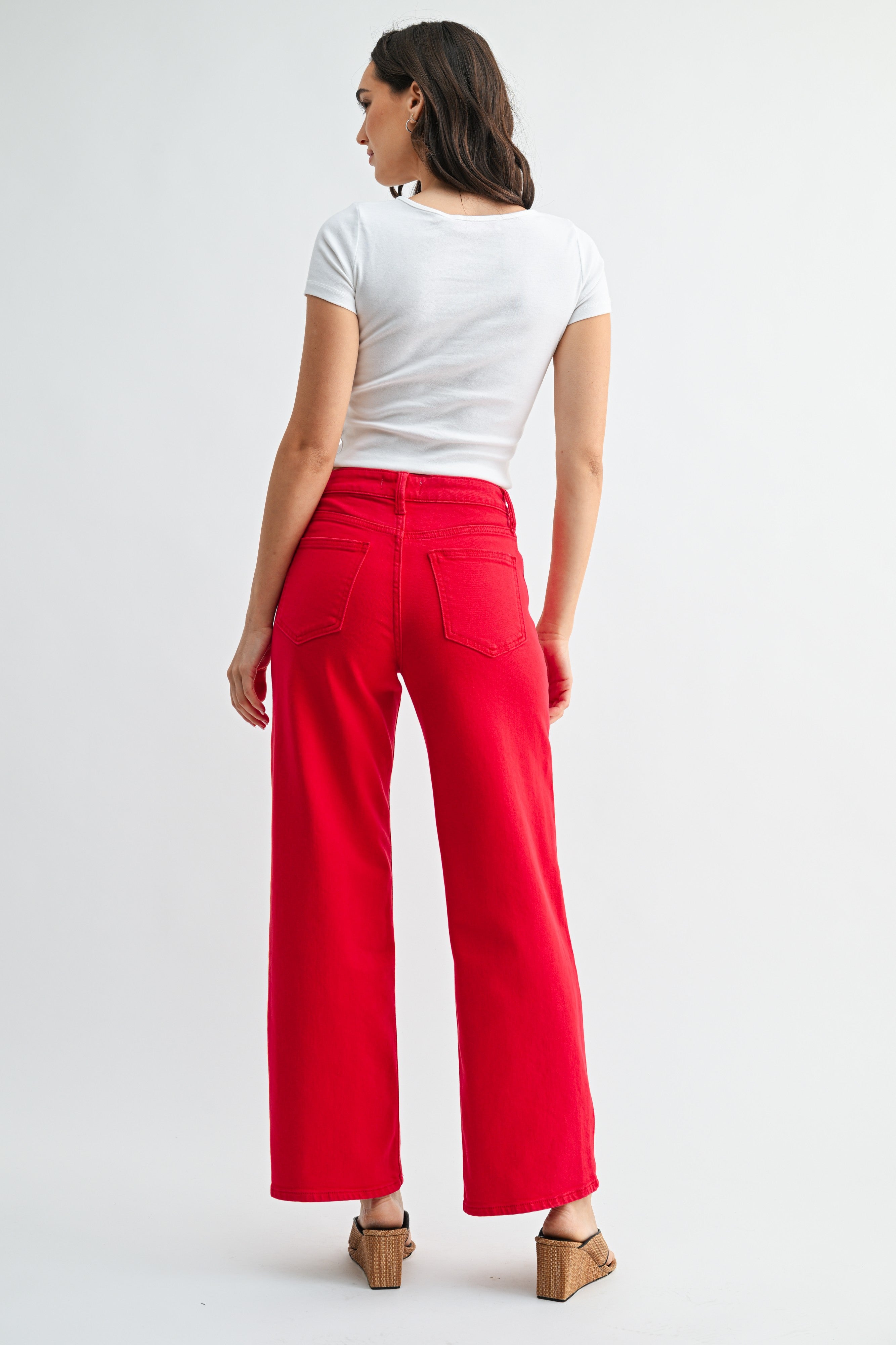 Woman wearing a white t-shirt and red pants on a plain background