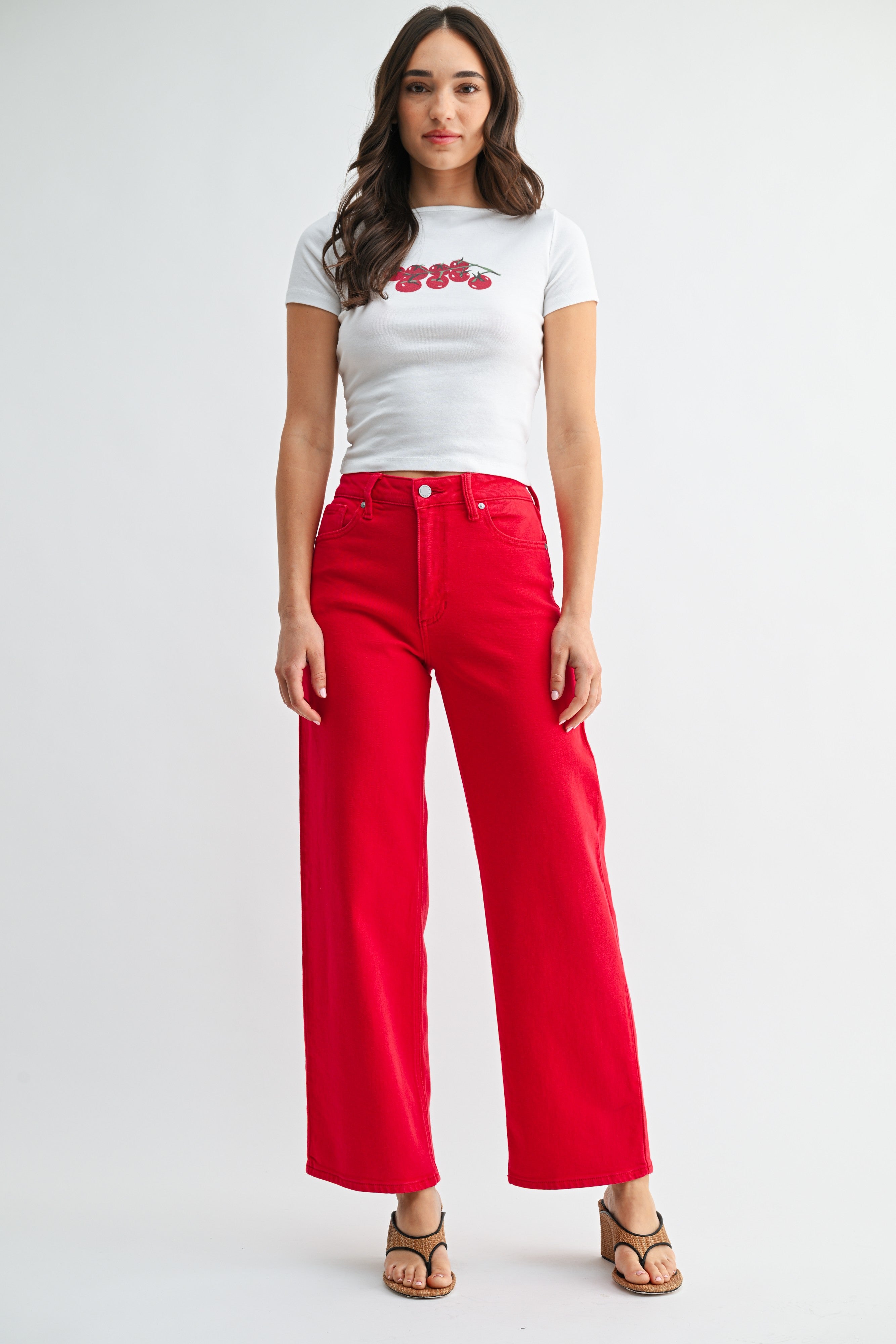 Woman wearing a white t-shirt with red graphics and red pants on a white background