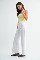 Woman wearing a yellow top and white pants on a white background
