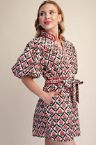Woman wearing a patterned dress with puff sleeves on a beige background