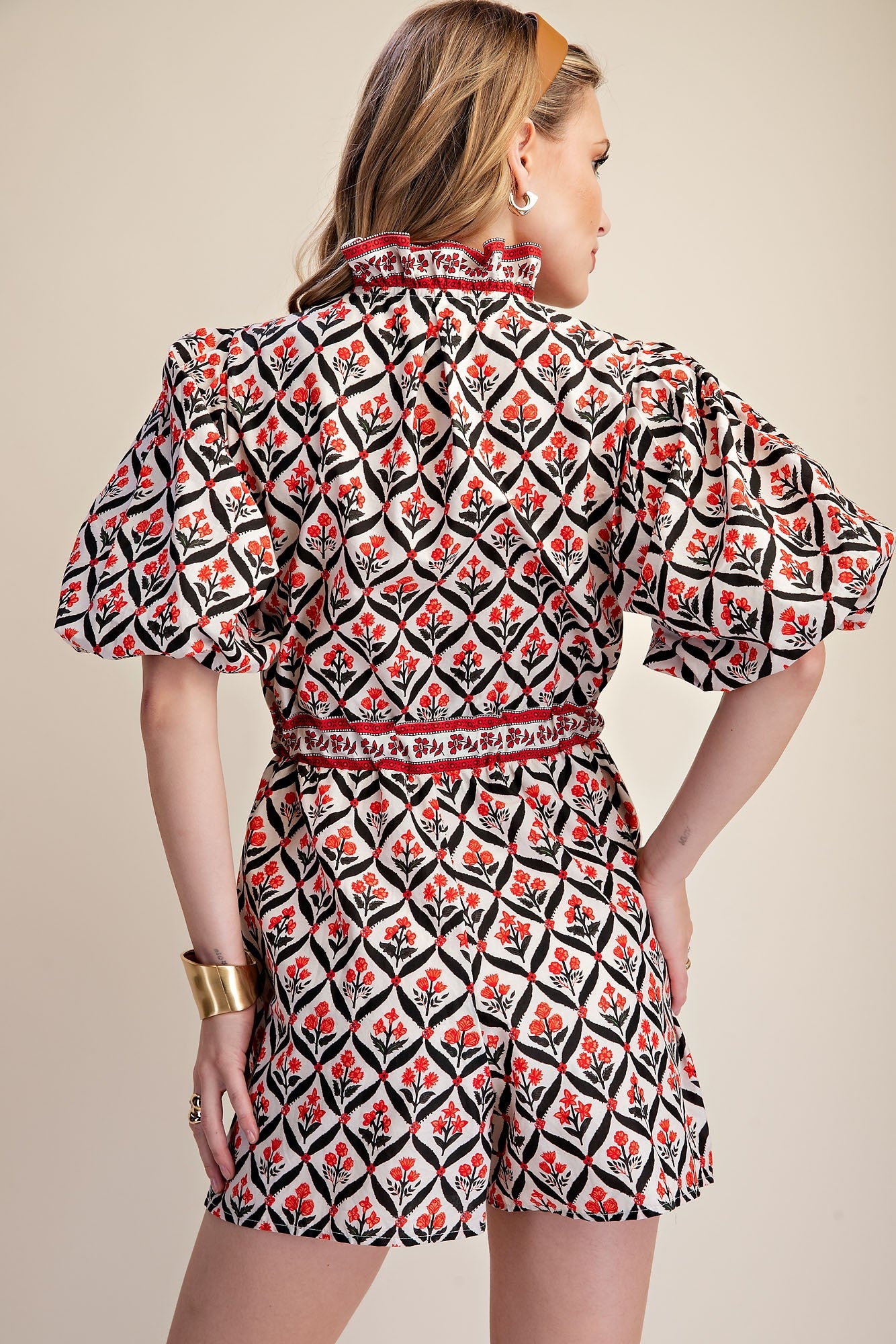 Woman wearing a patterned dress with puff sleeves on a beige background