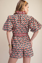 Woman wearing a patterned dress with puff sleeves on a beige background