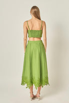 Woman wearing a green set with lace details on a plain background