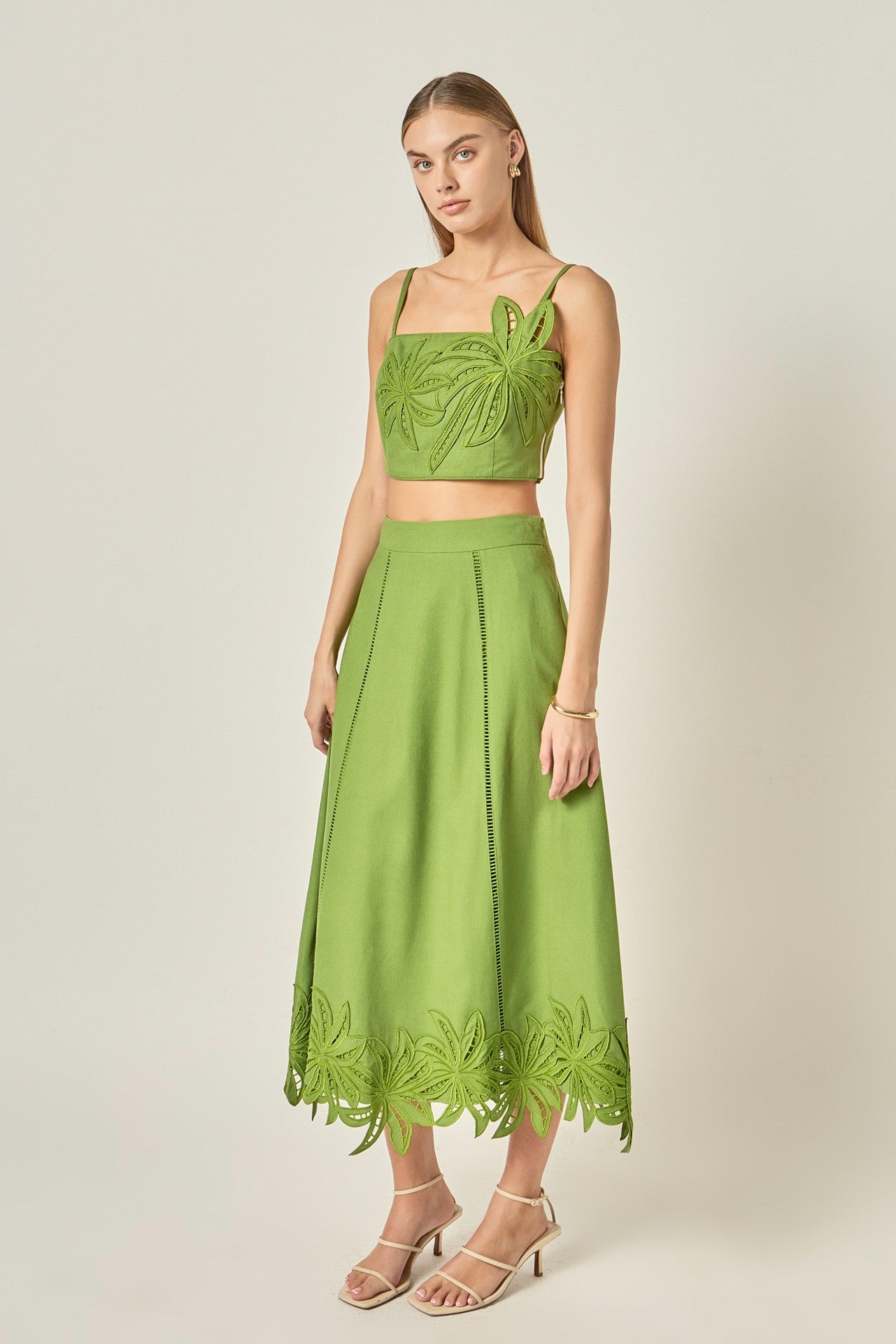 Woman wearing a green outfit with leaf patterns on a plain background