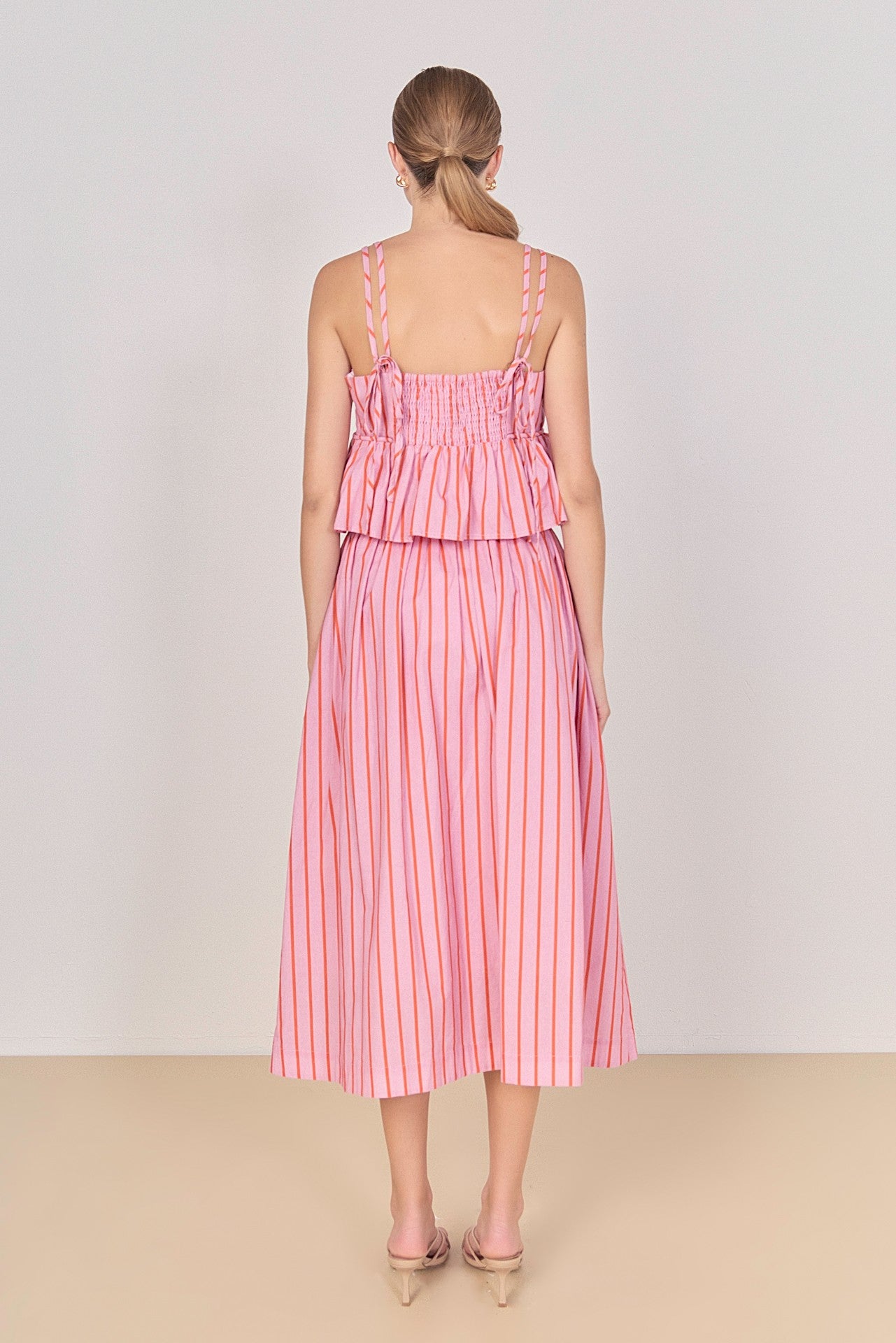 Woman wearing a pink and white striped dress on a plain background