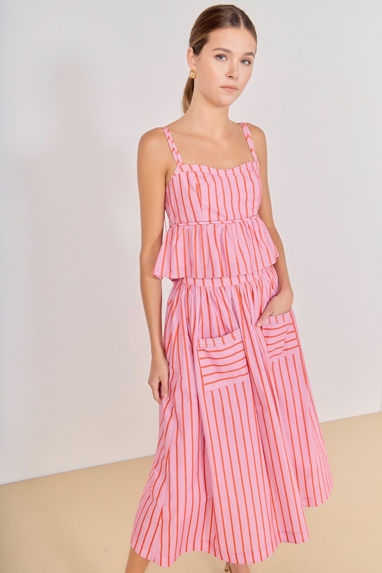 Woman wearing a pink and white striped dress against a plain background