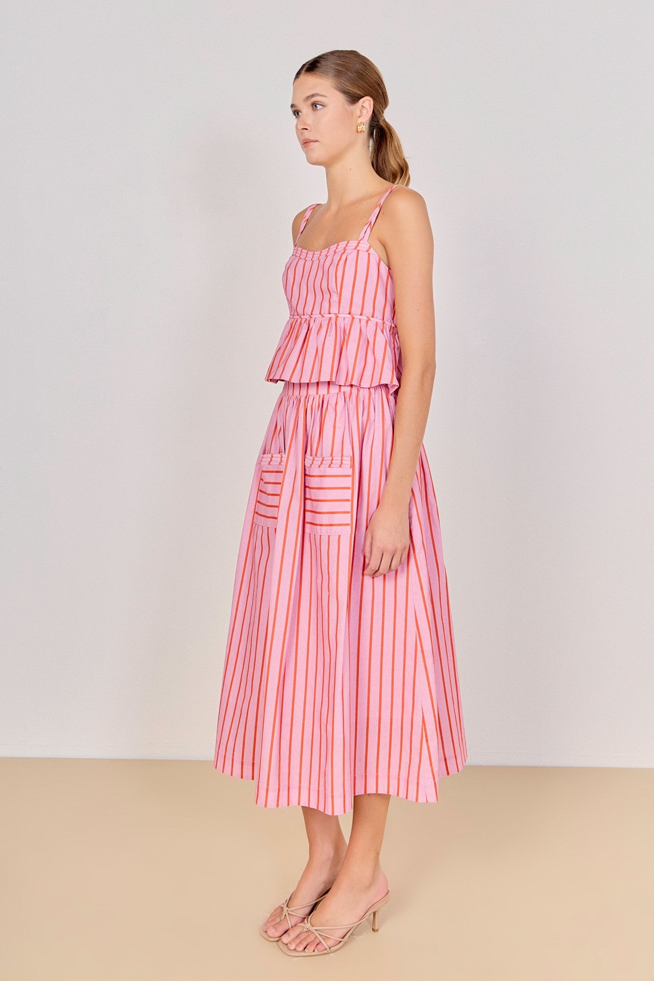 Woman wearing a pink striped dress against a white background