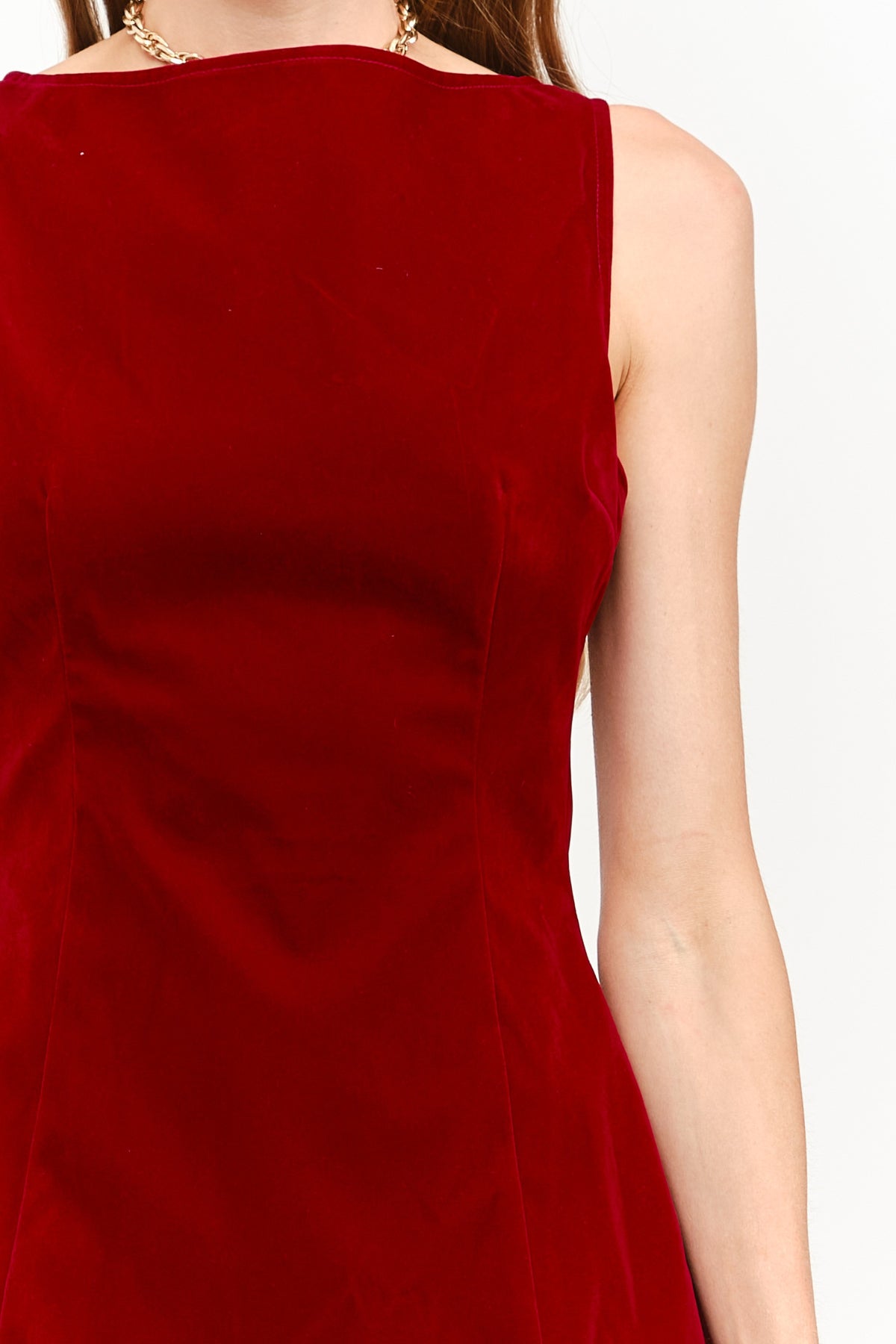 A close-up of a woman wearing a sleeveless deep red velvet dress, showing the back and side details against a plain white background.