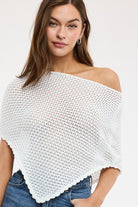Woman wearing a white crochet top with a plain background