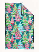A folded blanket featuring a colorful Christmas tree pattern on a dark teal background, with a small white tag on the lower edge.