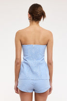 Woman wearing a blue checkered strapless top and shorts set on a white background