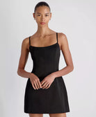 Woman wearing a black dress against a plain background
