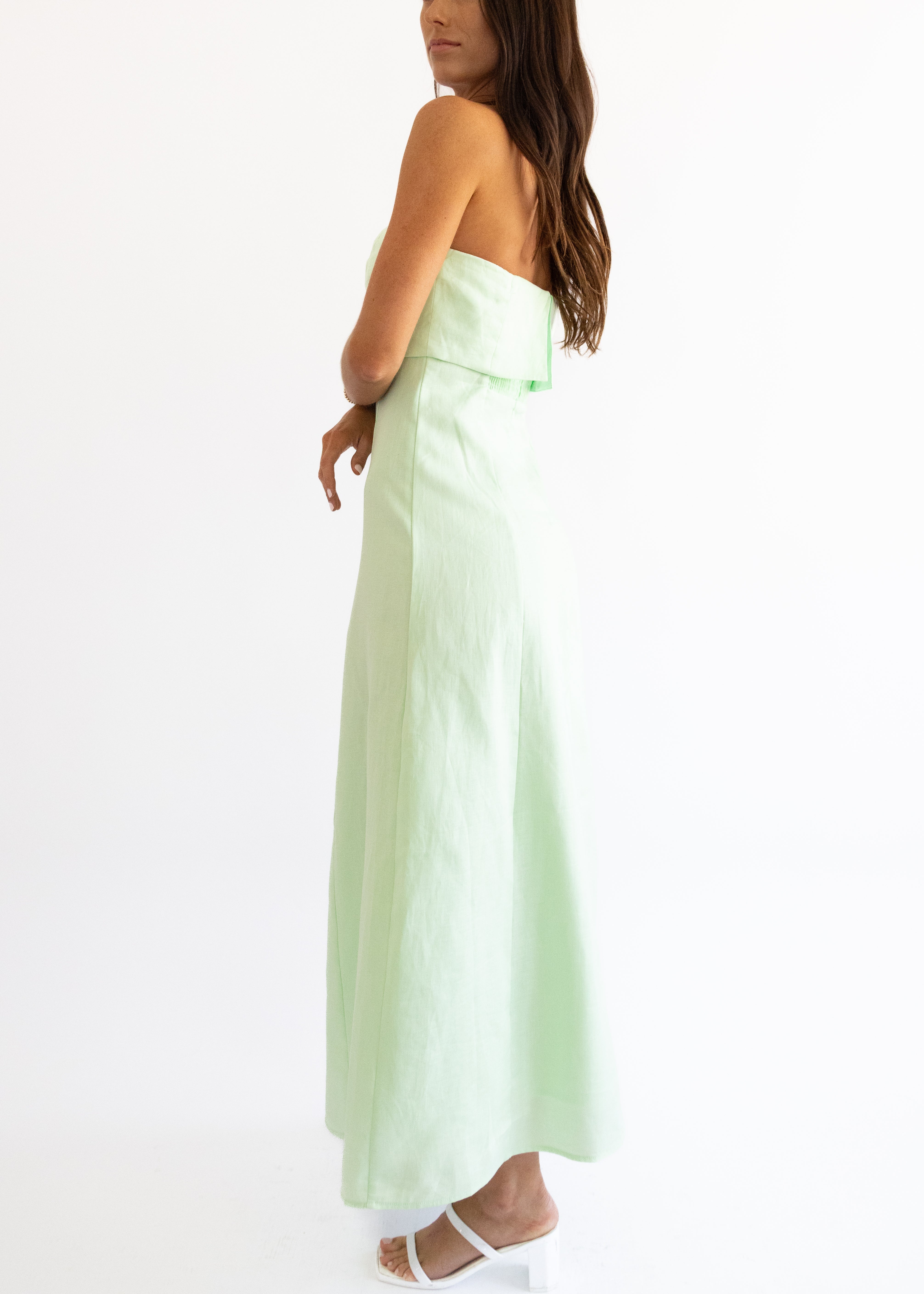 Woman wearing a light green strapless dress on a white background