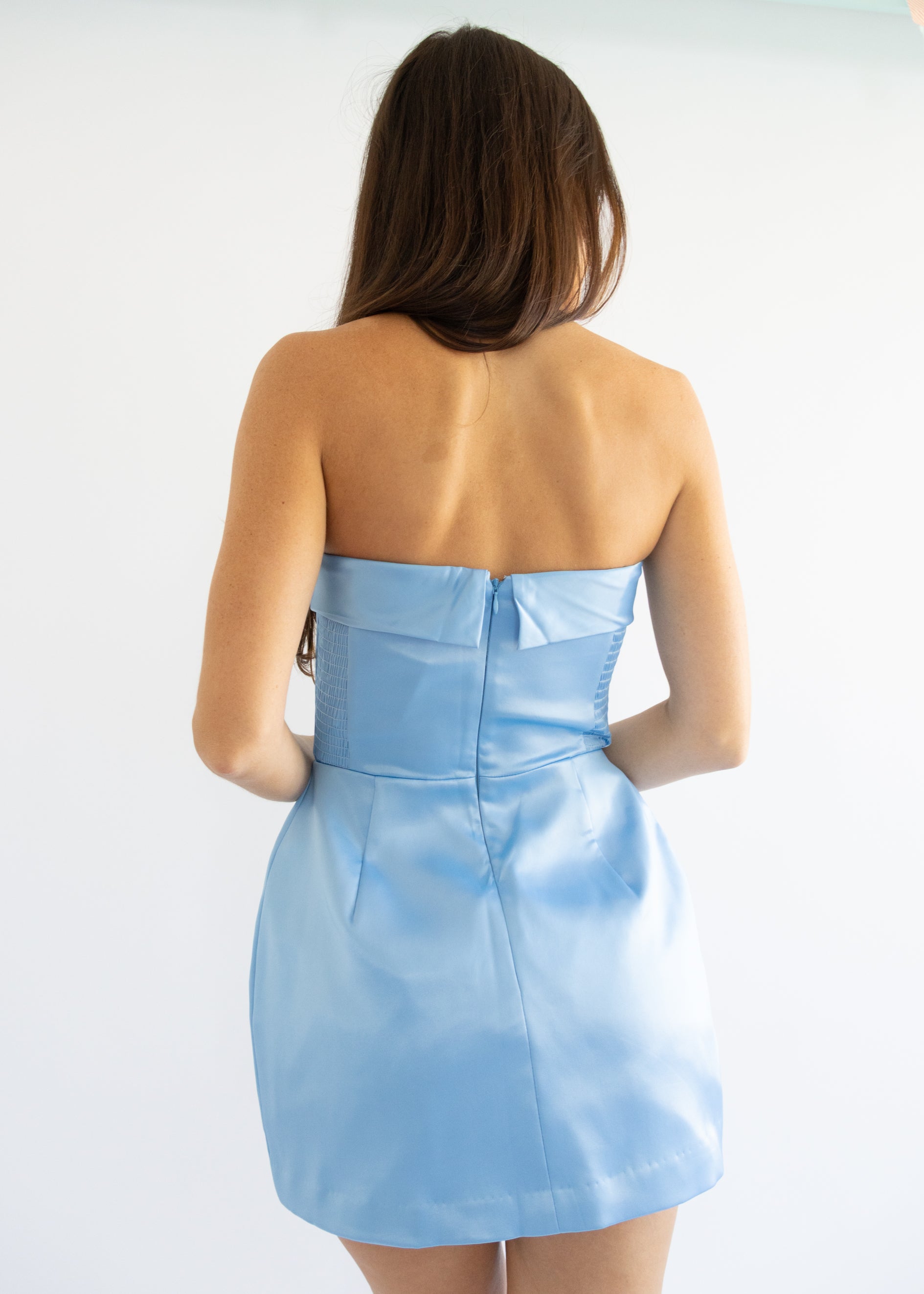Woman wearing a light blue strapless dress against a white background