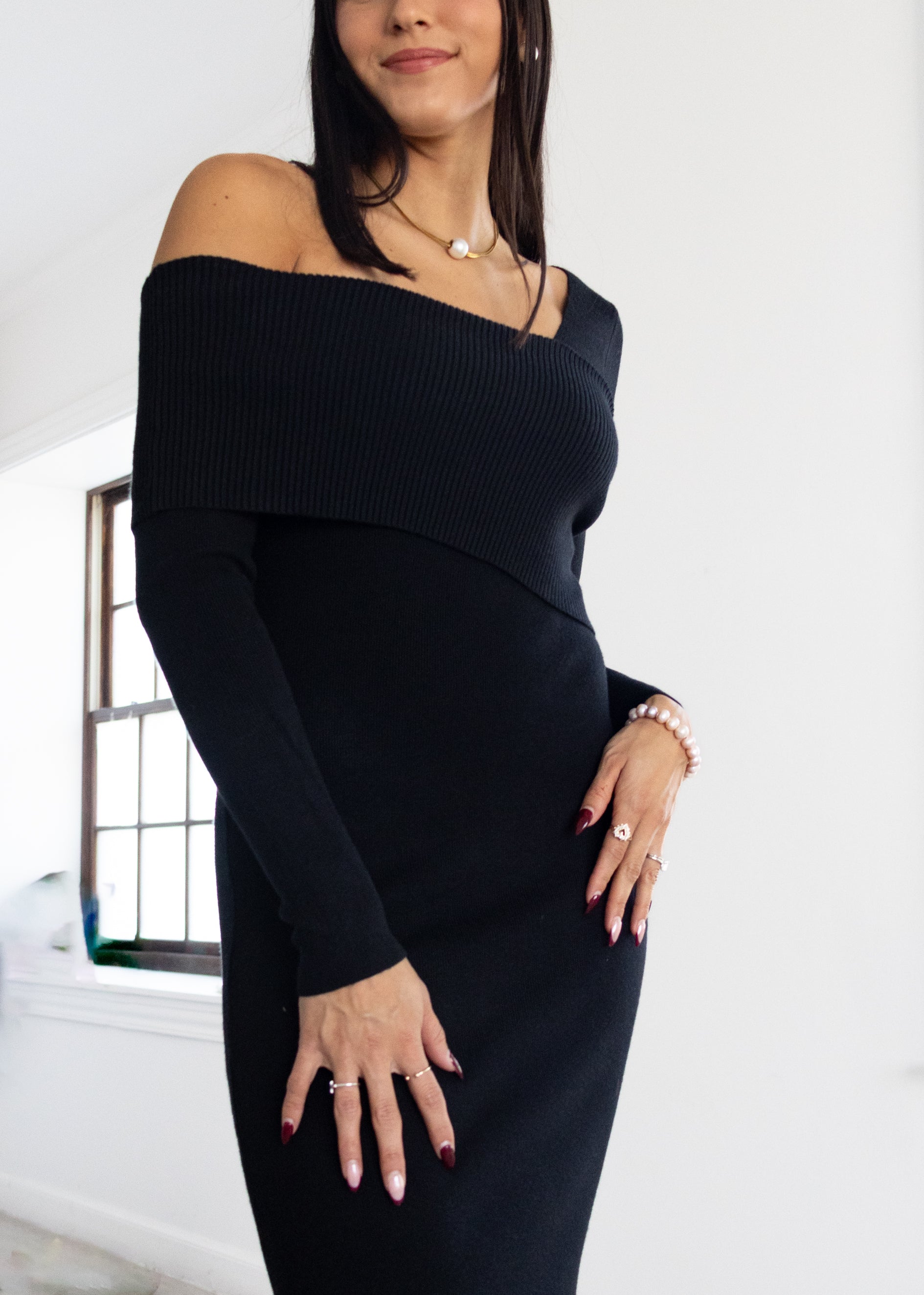 Woman wearing a black off-shoulder dress with a white background