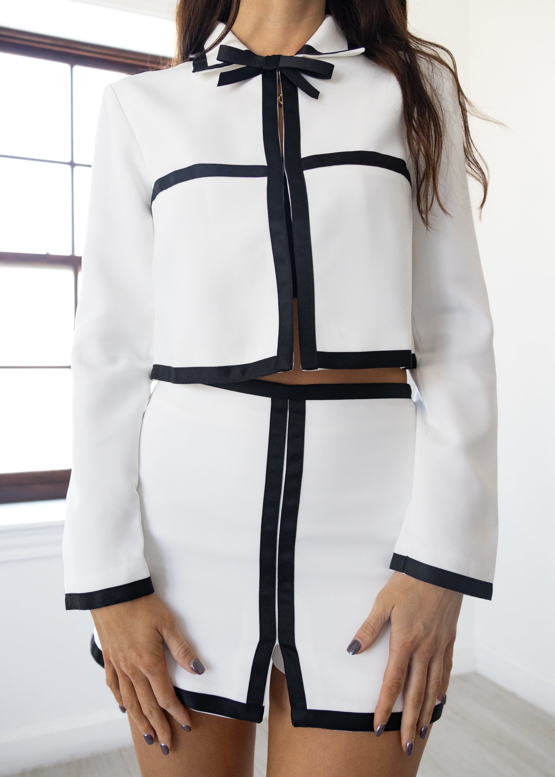 White outfit with black accents worn by a person indoors.