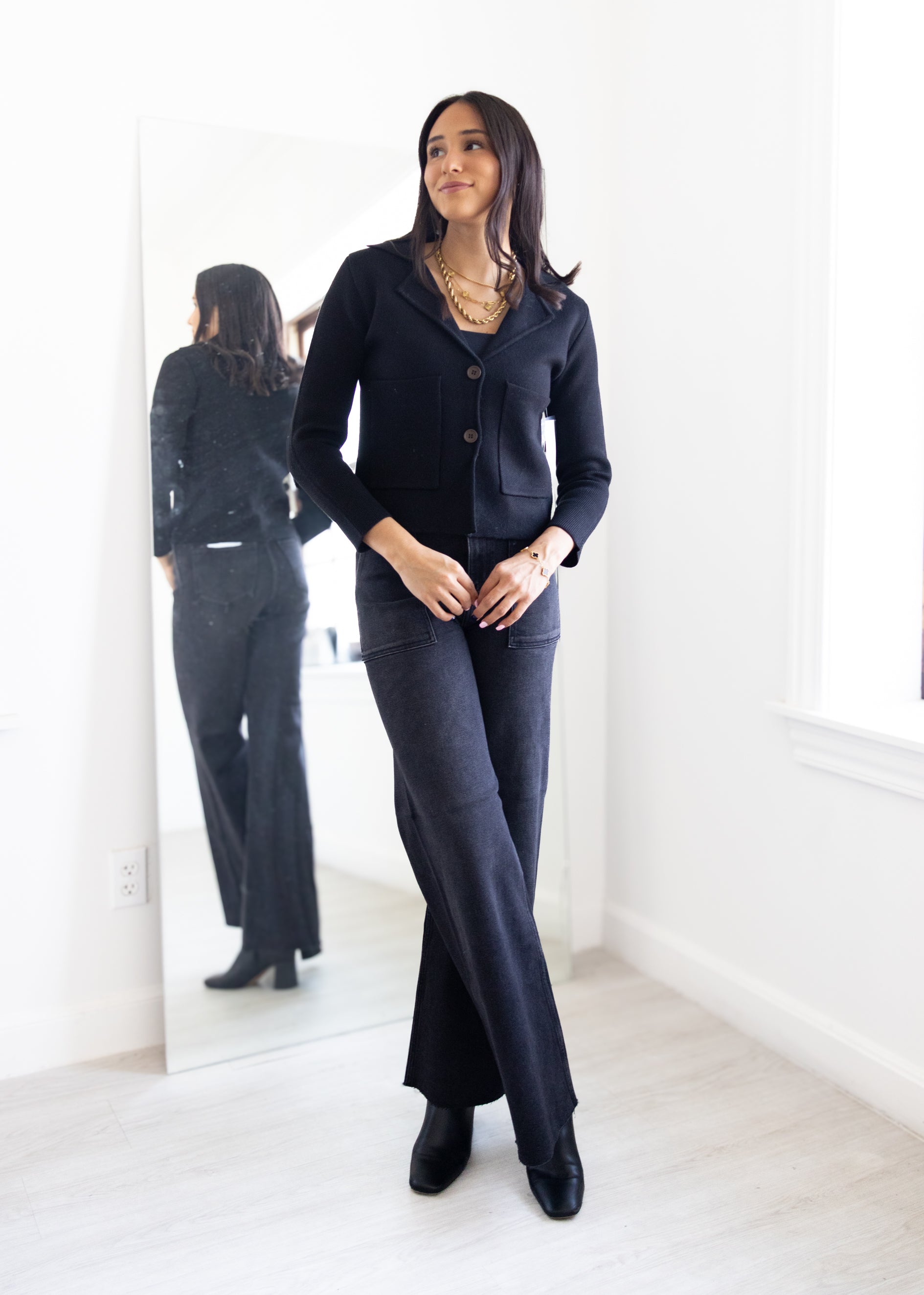 Woman in a navy suit standing in front of a mirror in a minimalistic room.