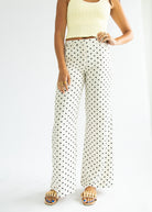 Person wearing a yellow top and polka dot pants on a white background
