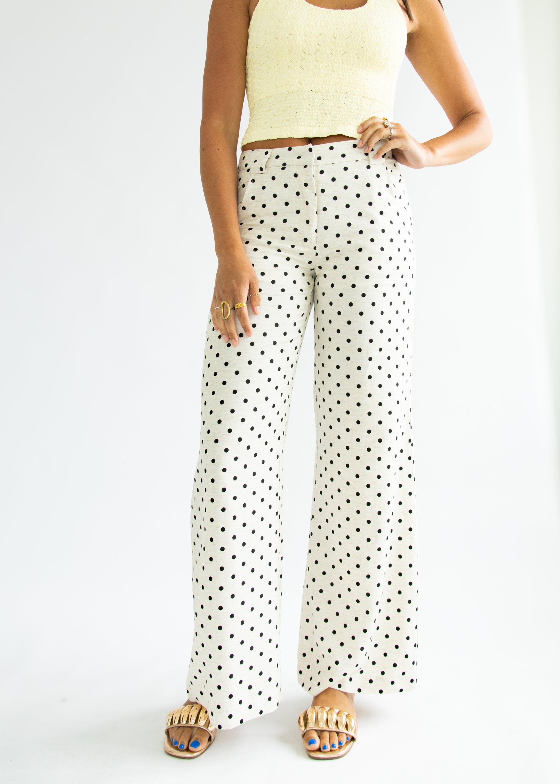 Person wearing a yellow top and polka dot pants on a white background