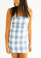 Woman wearing a blue and white checkered dress on a white background