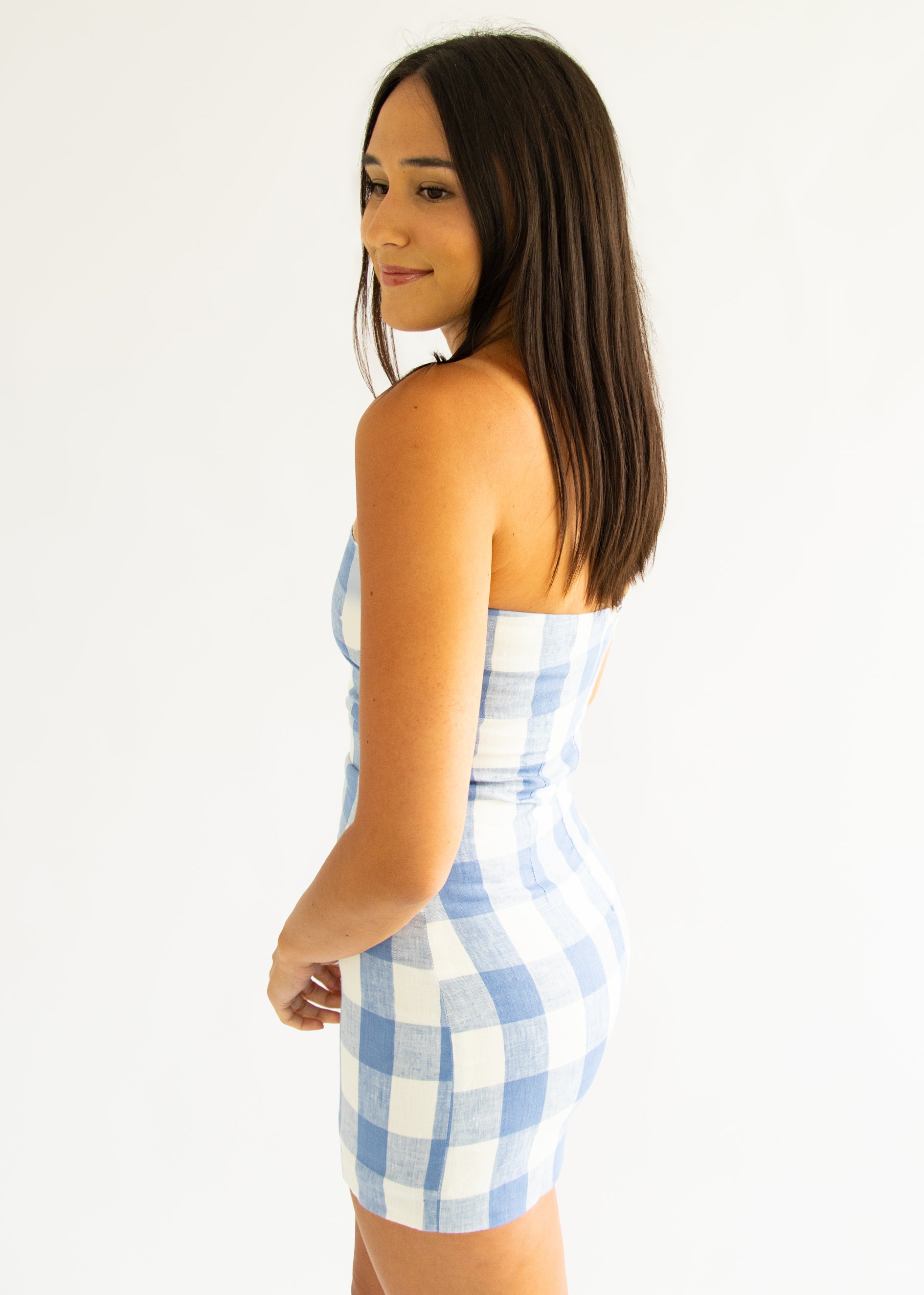 Woman wearing a blue and white checkered dress against a white background