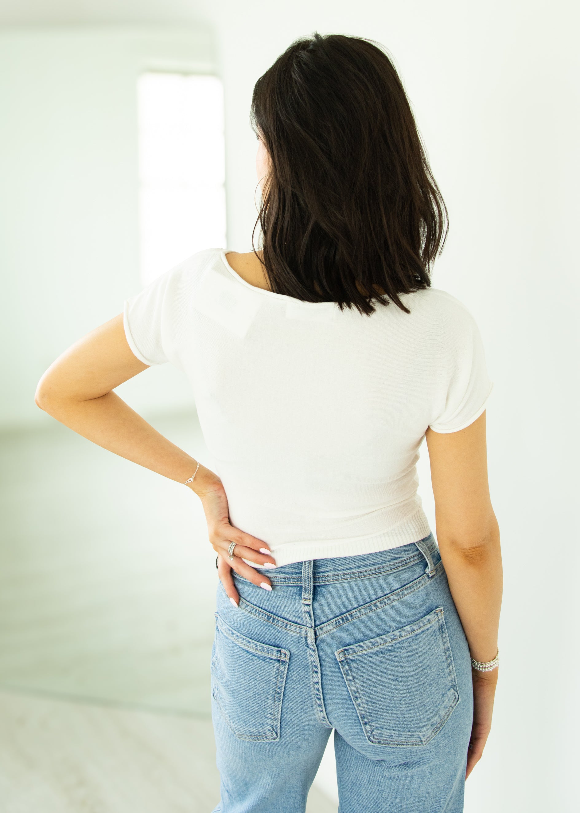 Person wearing a white t-shirt and light blue jeans against a plain background