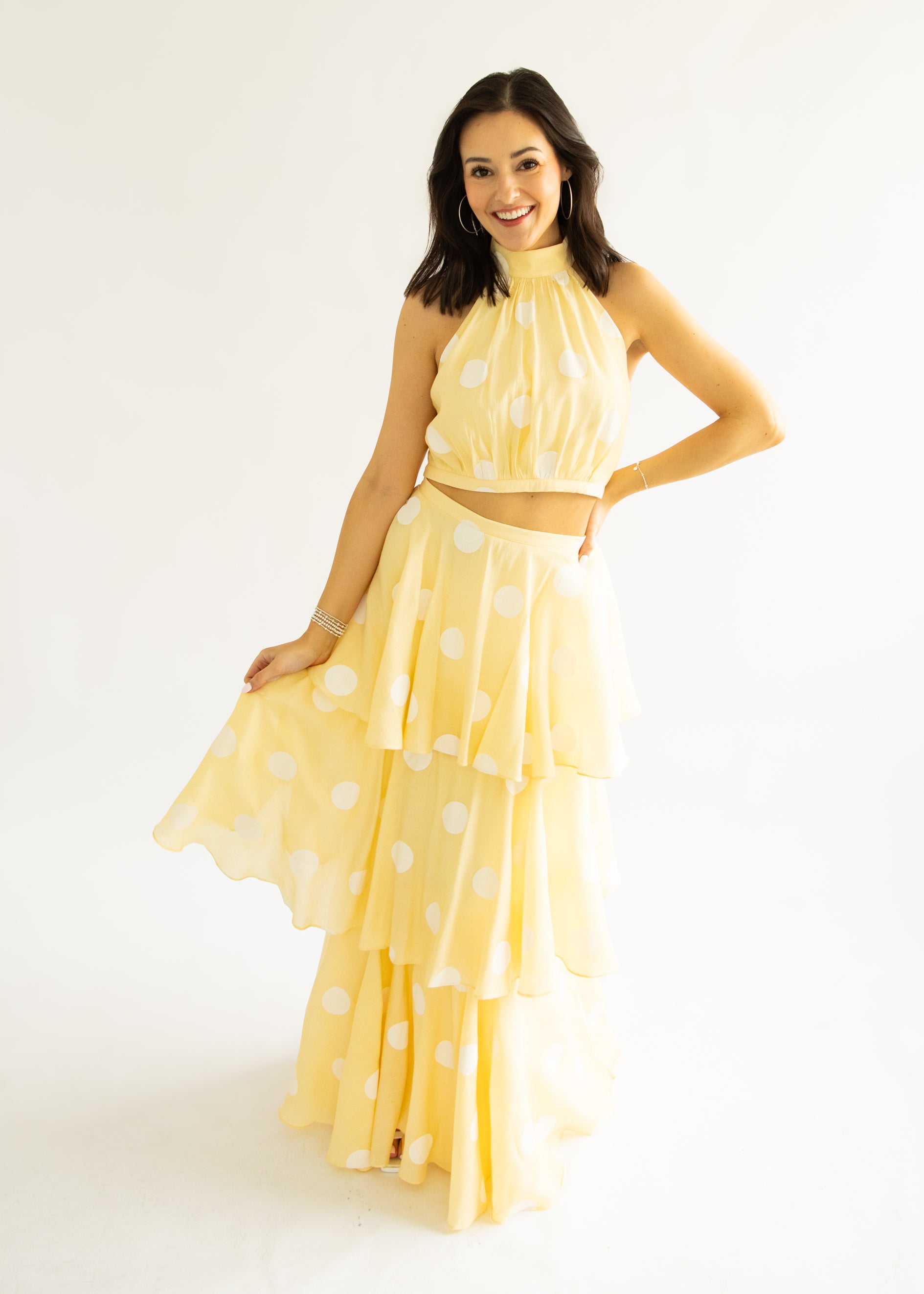 Woman wearing a yellow polka dot dress on a white background