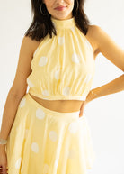 Woman wearing a yellow polka dot dress against a white background