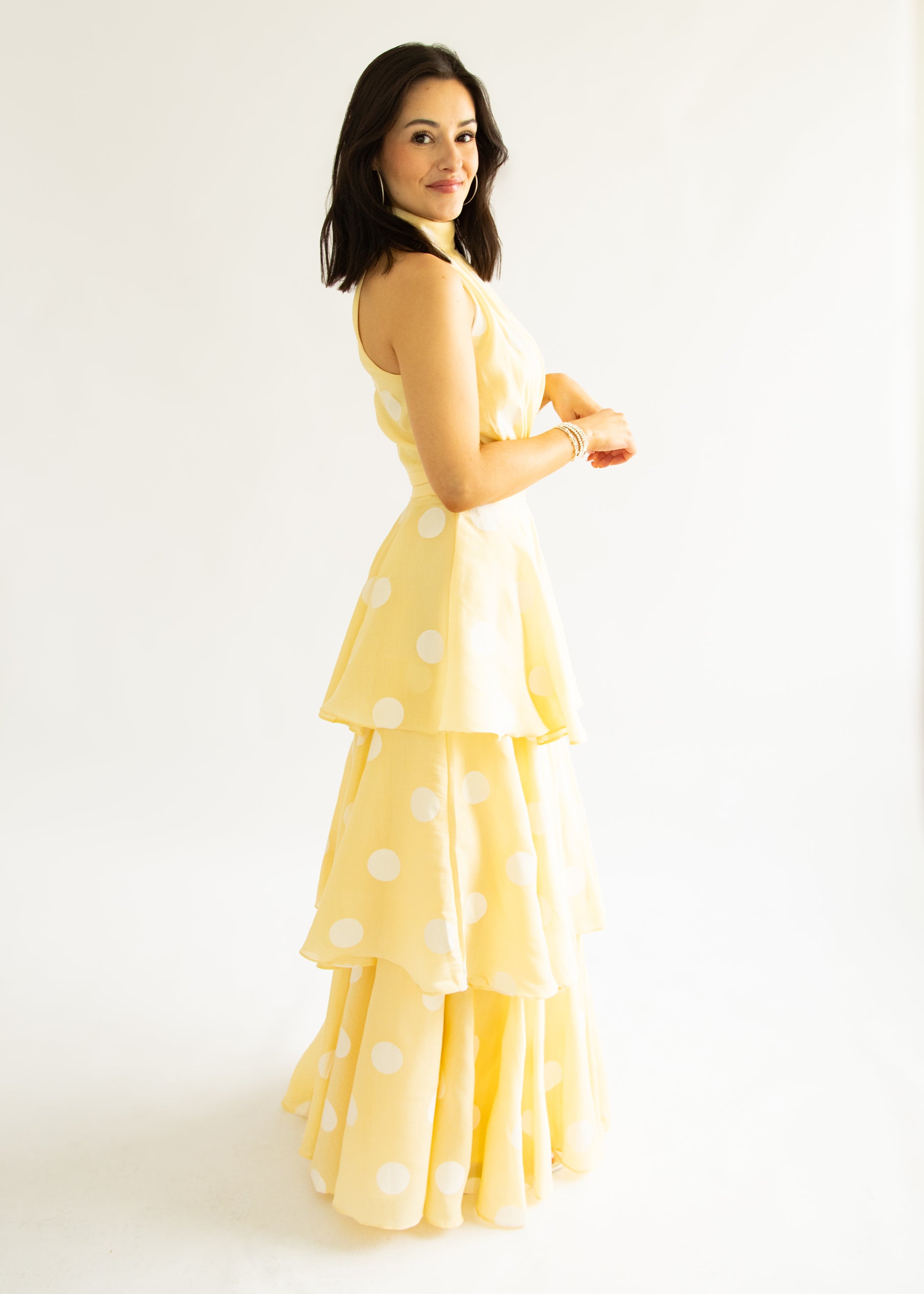Woman wearing a yellow polka dot dress against a white background